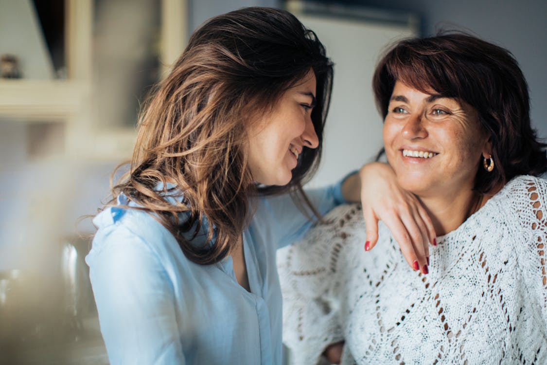 two women standing and smiling together.