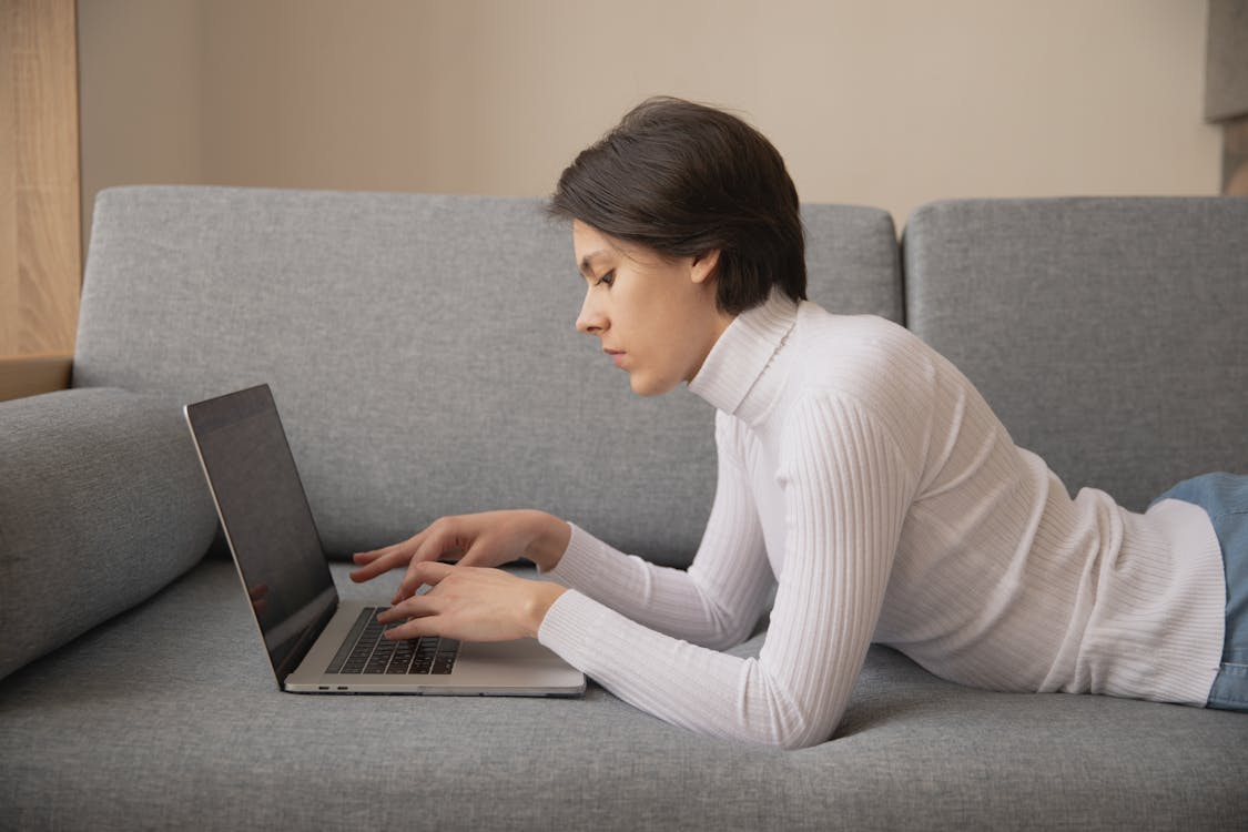 a woman using her computer on the couch.