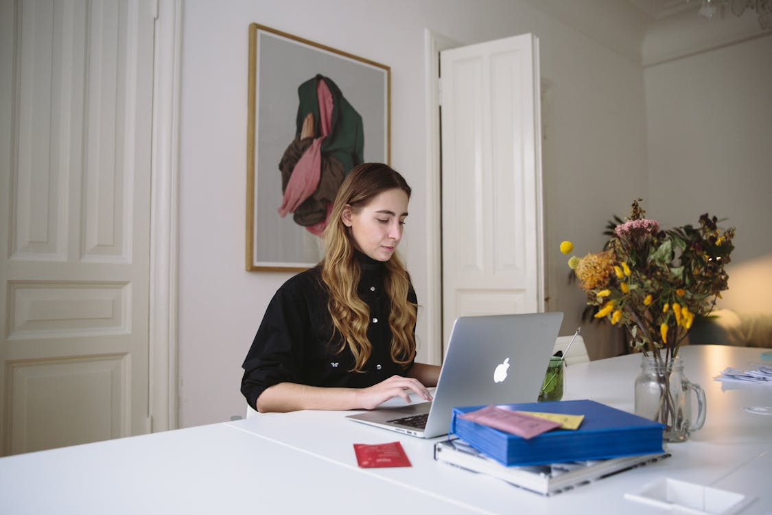 a woman in a black top using a gray laptop.