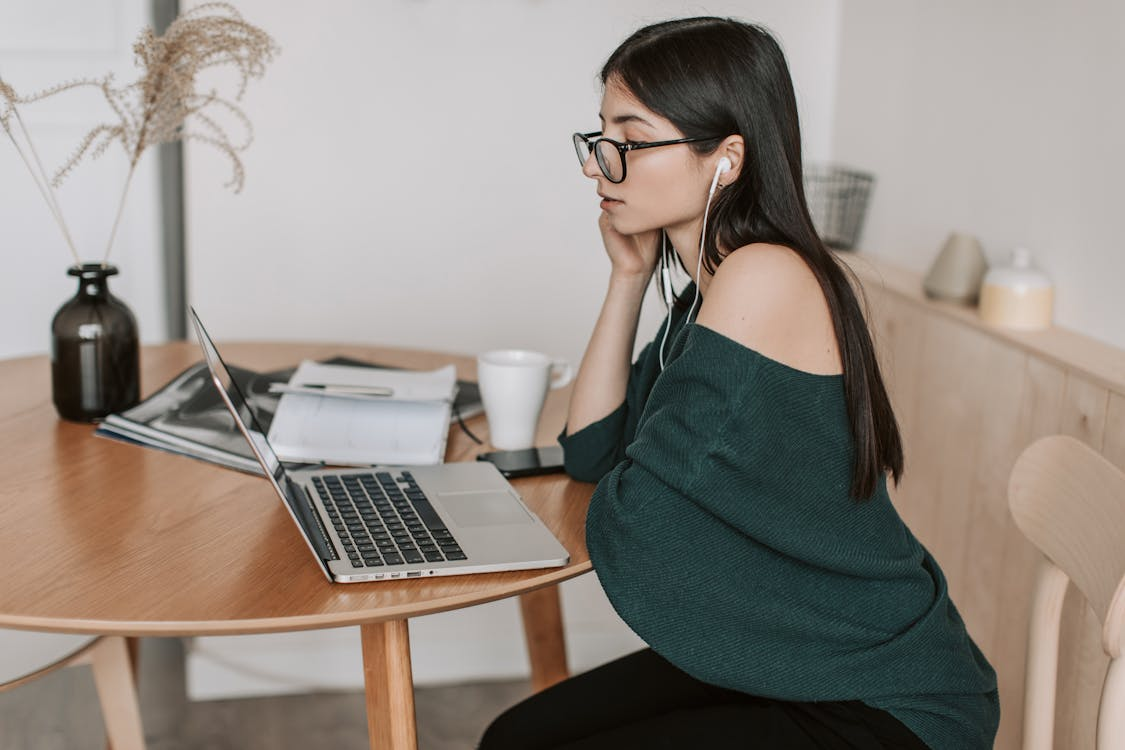 a woman in a green shirt looking at her computer.