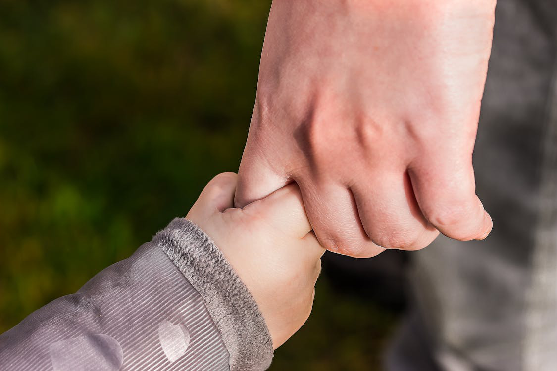 a father holding a child’s hand.